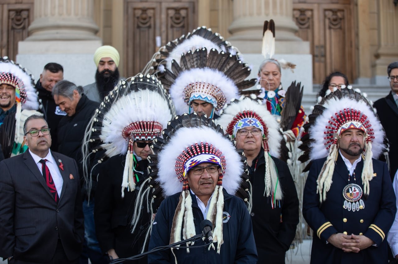 default-401 A First Nation chief speaks at a microphone with several others standing behind him.